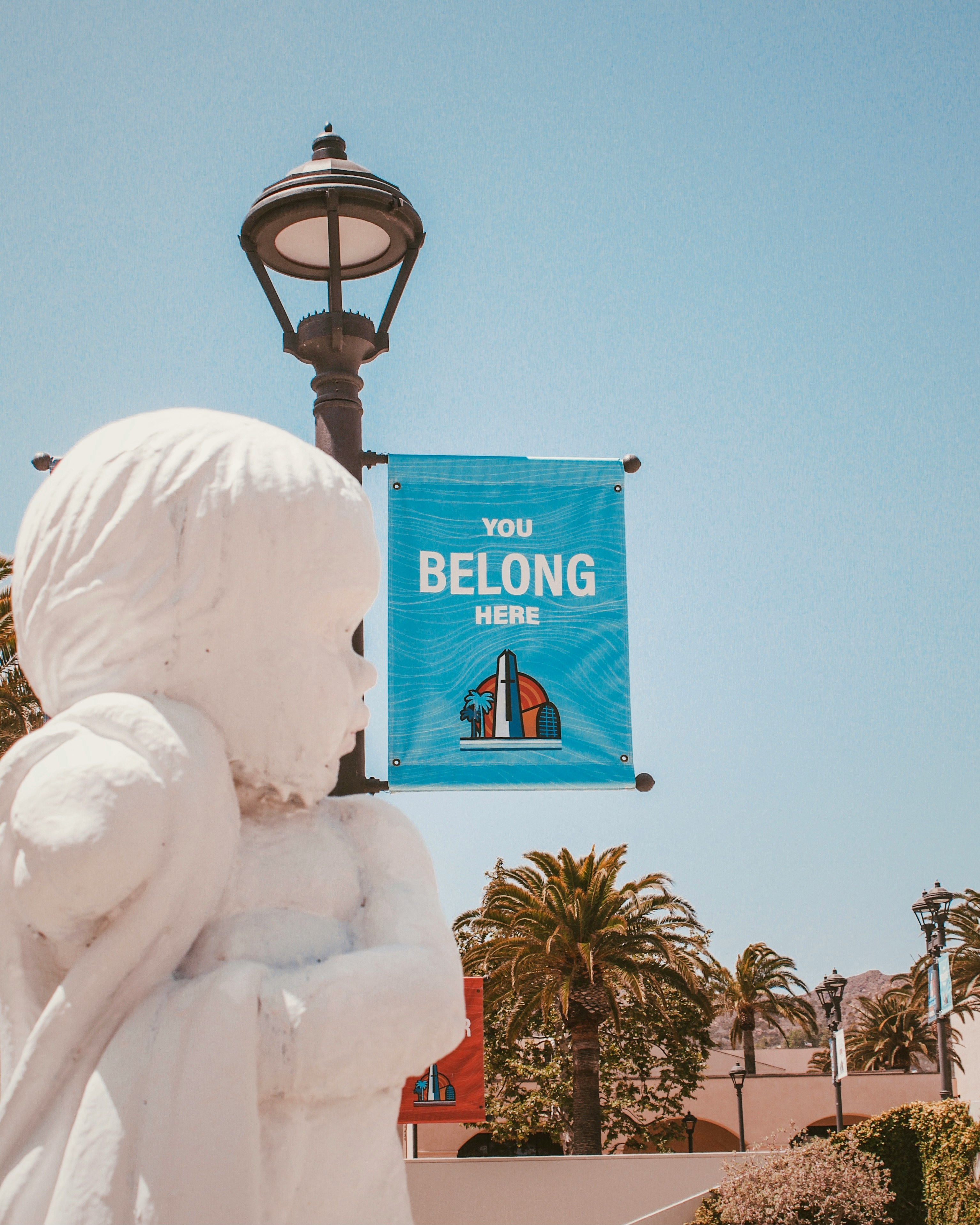 white concrete statue near green palm trees during daytime